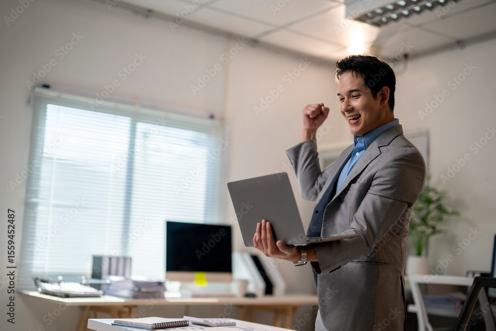 Obraz premium A man in a suit is holding a laptop and smiling