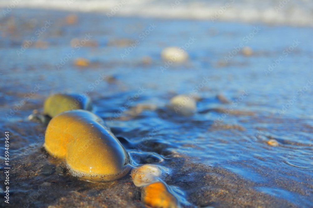 Obraz premium Colorful Pebbles and Gentle Waves on Curracloe Beach – Tranquil Summer Evening by the Irish Sea in County Wexford, Ireland with Warm Sunlight, Shimmering Water, and Natural Coastal Beauty