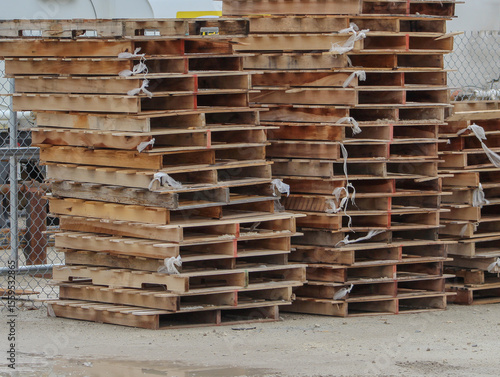 Stalked used wooden pallets outside a warehouse.