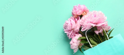 Foto Shopping bag with beautiful pink peonies on turquoise background with space for