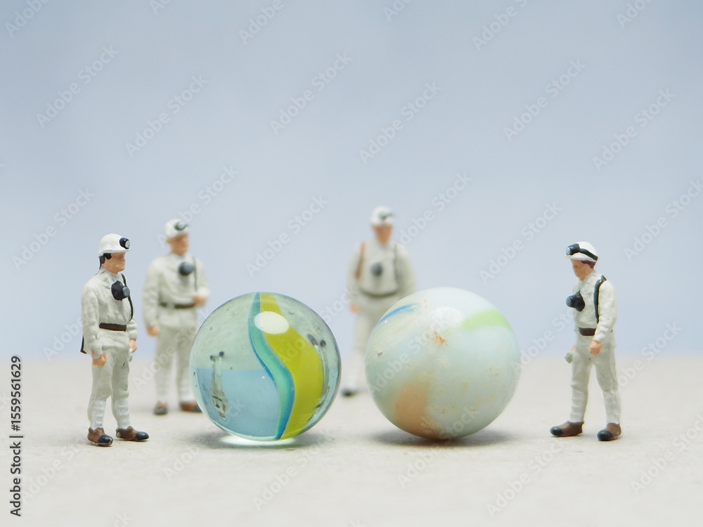 Obraz premium Mini toy of action figure at outdoor with blurred background. Toy photography concept design. Minifigure of scientist character with marble stone. People wear hazmat suit.