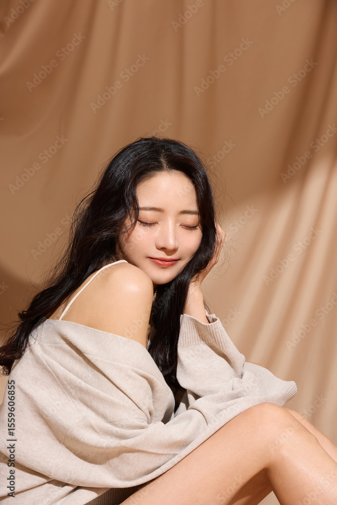 Naklejka premium ベージュの布地背景で撮影をした若い女性の高級感のある美容ポートレート