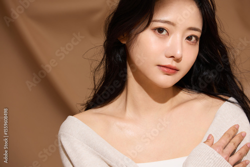 ベージュの布地背景で撮影をした若い女性の高級感のある美容ポートレート