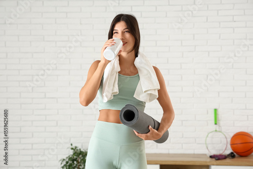 Young woman with yoga mat and towel in gym