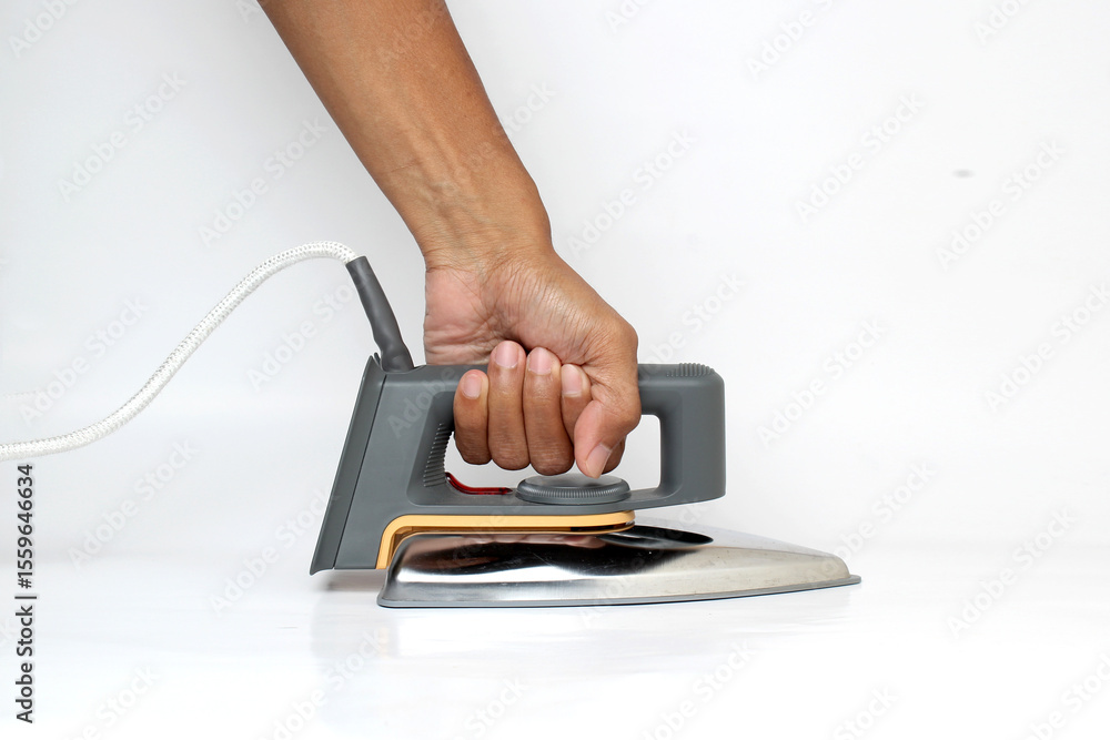 Fototapeta premium A hand firmly grasps a classic dry iron, ready for pressing clothes, against a clean white background