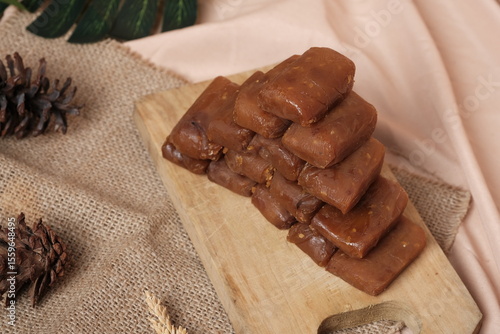 Stack of Jenang Ketan Dodol, Indonesian sweet snack made from glutinous rice flour, coconut milk, brown sugar and pandan leaves, set on rustic background