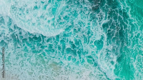 Aerial view of surfers waiting for waves on a tropical beach. Surfers paddle out to sea on a sunny day and turquoise sea. Waves crashing on a tropical island shore