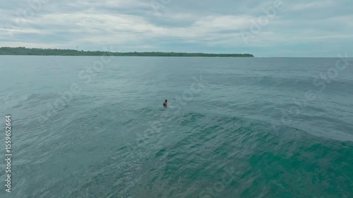 Surfers in action on big waves off a tropical beach. Aerial view of surfers enjoying the waves