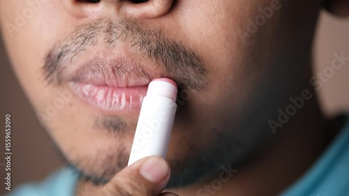 Close-up of Southeast Asian Man Lips Applying Lip Balm for his dry lips
