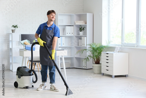 Wallpaper Mural Young male janitor with modern vacuum cleaner cleaning floor in office Torontodigital.ca