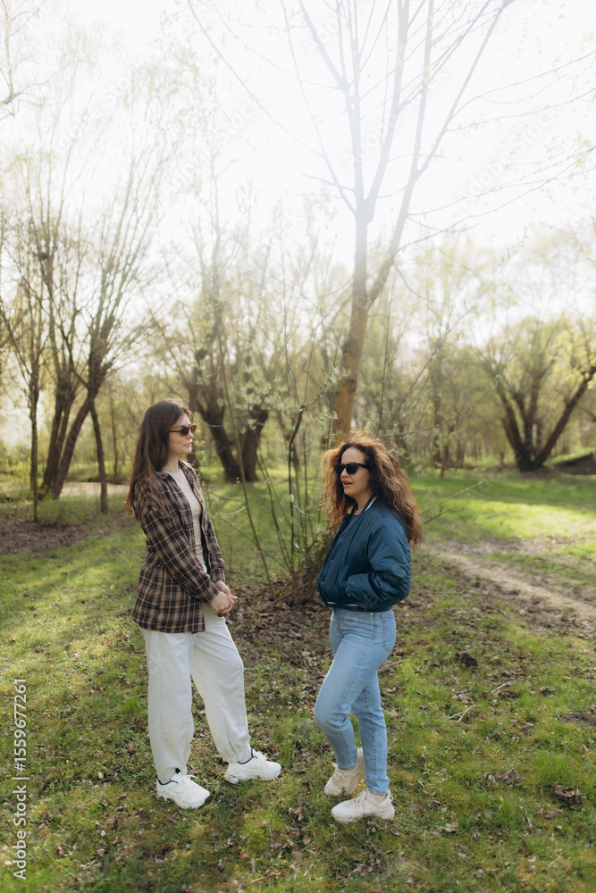 Fototapeta premium Women Engaging in Conversation Outdoors in a Sunny Forest Setting
