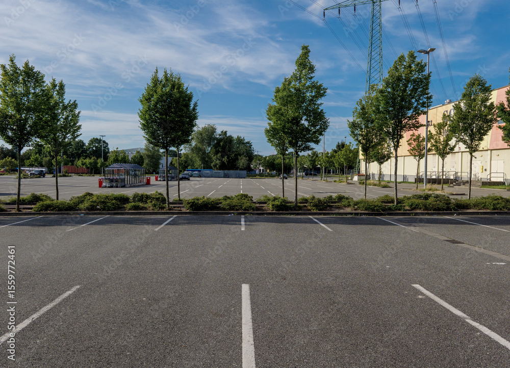 Fototapeta premium Empty Supermarket Parking Lot in Bright Sunshine, Showing Urban Stillness, Everyday Infrastructure, and the Stark Clarity of a Quiet Commercial Space