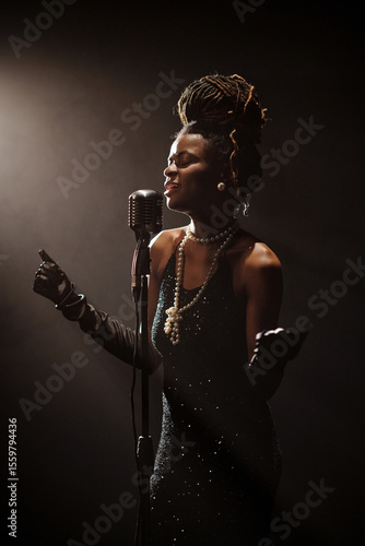 Photography African American woman singing into vintage microphone on stage, wearing elegant