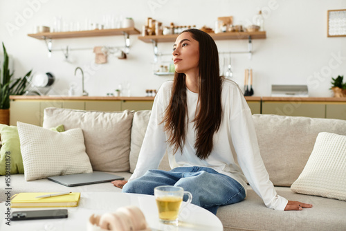 Young pretty woman enjoying a cozy moment at home while sipping tea and reflecting peacefully