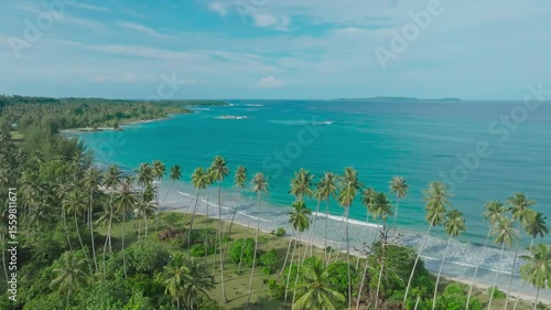 An aerial view of a tropical island with white sand beaches and turquoise waters. Waves crashing on a white sandy tropical beach