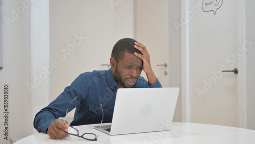 Young African Man with Loss on Laptop