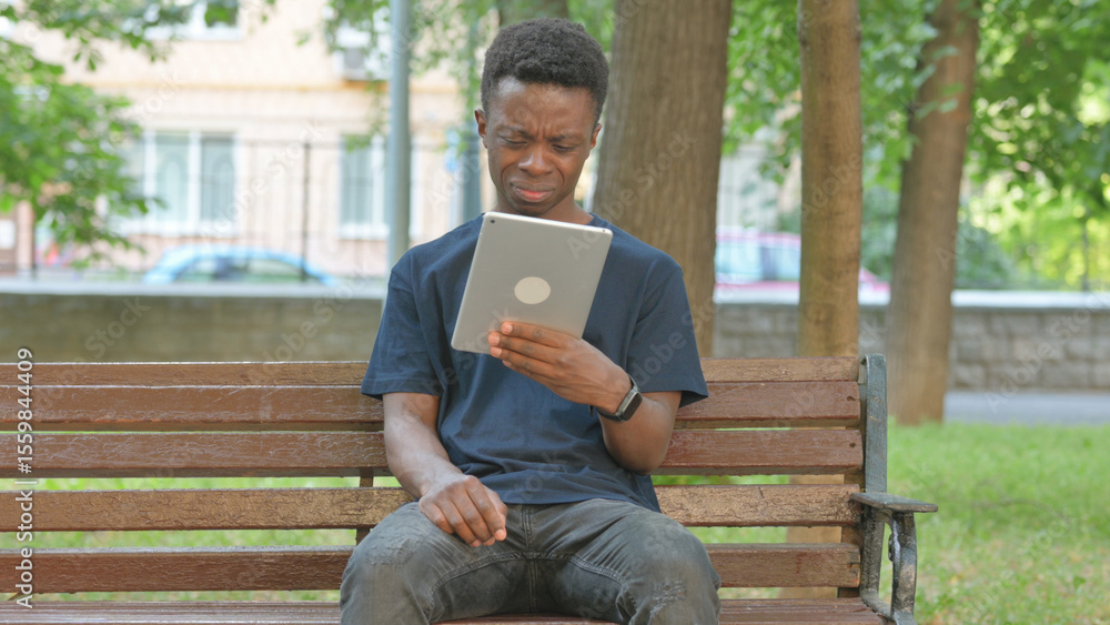 Fototapeta premium Casual African Man Expressing Disbelief While Using a Tablet
