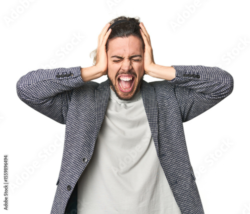 Canvas Print Young businessman in casual blazer covering ears with hands trying not to hear too loud sound
