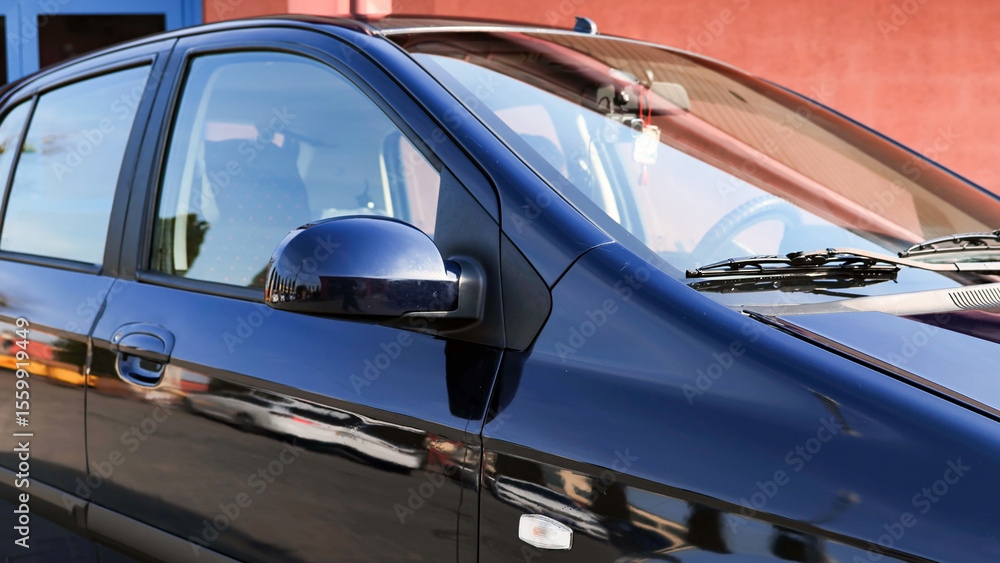 Fototapeta premium Clean and shiny dark blue car parked near building reflecting surrounding in the paint