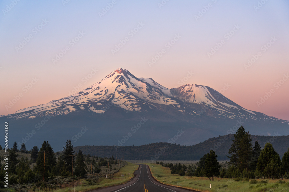 Fototapeta premium Amazing early morning view of Mount Shasta Volcano, California, USA from US highway 97, with the first rays of sunlight hitting the summit
