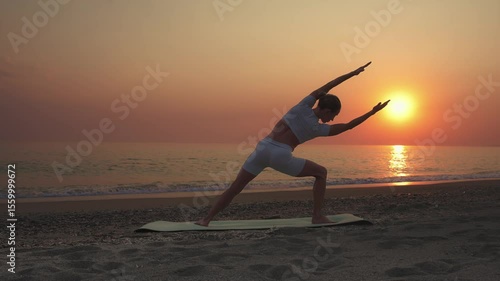 Woman Practicing Humble Warrior Yoga Pose on the Beach at Sunrise