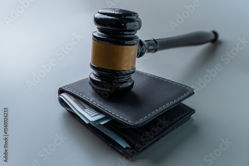 A judge's gavel on a wallet overflowing with US hundred-dollar bills. Wage garnishment, fines, legal fees concept.
