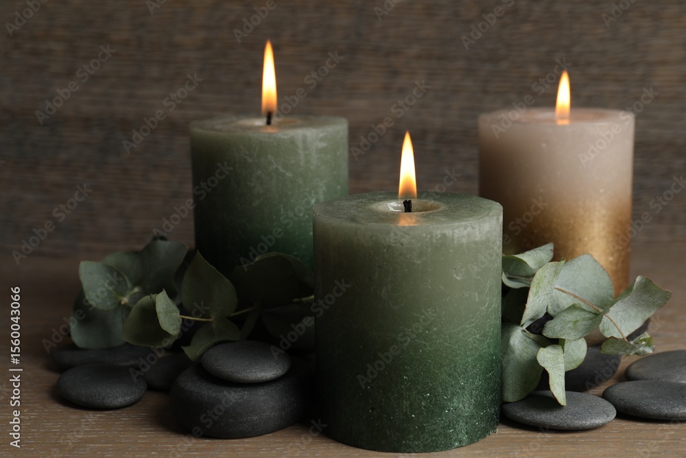 Burning candles, stones and eucalyptus branches on wooden table, closeup Burning candles, stones and eucalyptus branches on wooden table, closeup