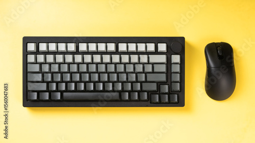 Mechanical keyboard with gradient gray keycaps paired with a black wireless mouse on a bold yellow background, creating a clean and modern office tech setup