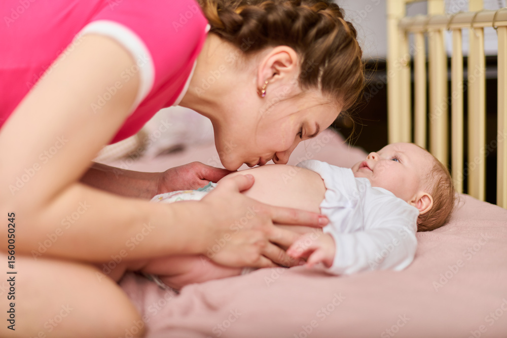Young woman with braided hair kisses baby girl in cozy room. Warm lighting enhances tender moment. Pink tones dominate intimate, loving atmosphere Young woman with braided hair kisses baby girl in cozy room. Warm lighting enhances tender moment. Pink tones dominate intimate, loving atmosphere