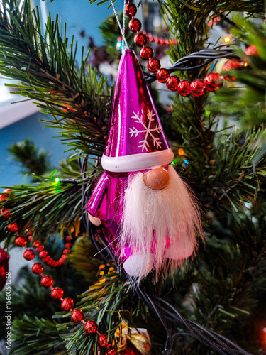 Christmas tree with silver and gold decoration, pink dwarf, red beads and other decorations in the background. New year
