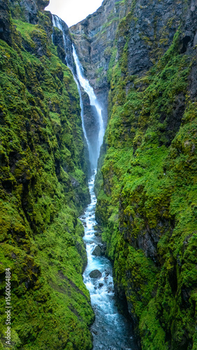 Tableau sur toile Majestic waterfall cascading through lush green canyon in Icelands breathtaking