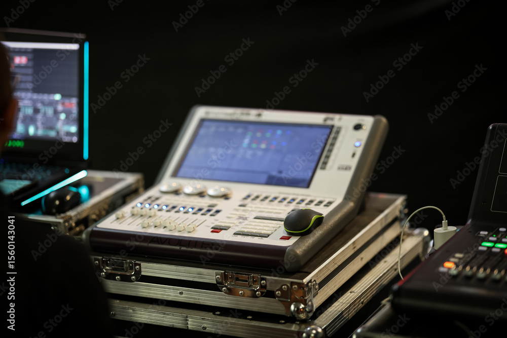 Fototapeta premium Professional lighting control console with touchscreen interface and faders, used for live stage event management and show lighting synchronization. Indoors setup.