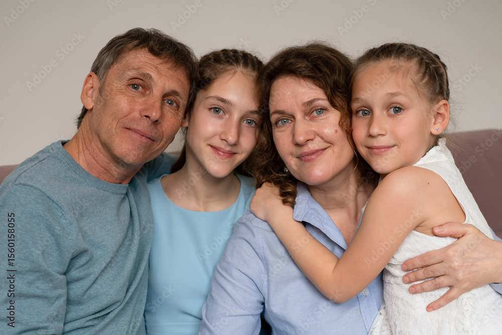 Obraz premium Family Sofa Bonding, parents, daughters, smiling, looking at device, indoor, quality time, modern day.