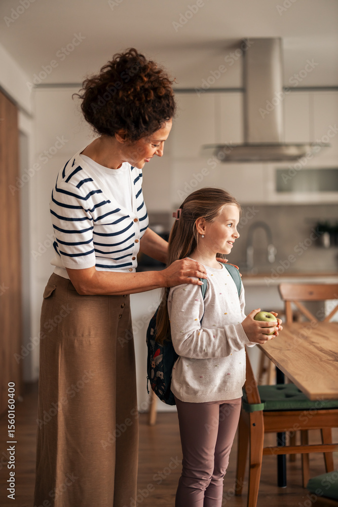 Fototapeta premium Mother Preparing Daughter for School in the Morning Home Kitchen