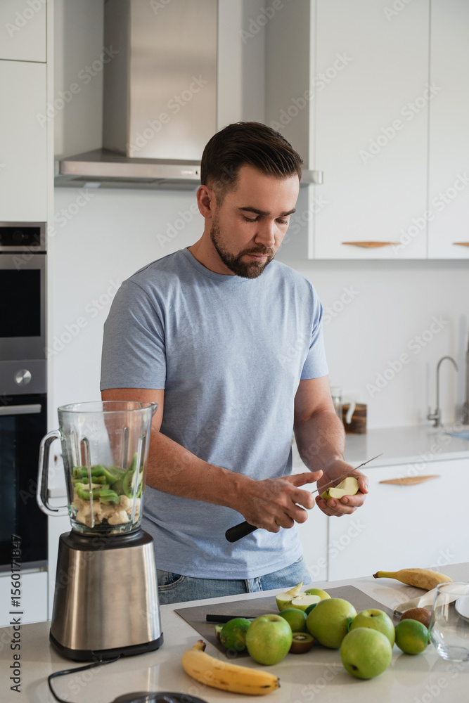 Fototapeta premium Man Preparing Fresh Fruit Smoothie in Modern Kitchen