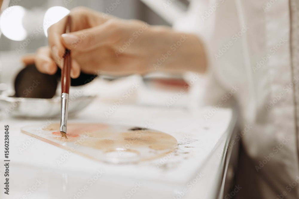 Fototapeta premium Makeup artist, makeup, brush paint concept. Makeup artist dips brush into paint. Close-up