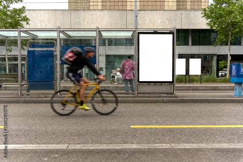Cyclist in front of tram stop with empty billboard.