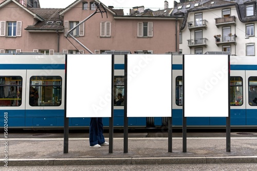 Tram stop in Zurich with three portrait format billboards.