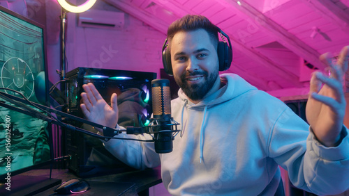 Fototapeta Naklejka Na Ścianę i Meble -  Caucasian smiling talking microphone at camera guy male gamer man streamer influencer blogger in headphones record channel online vlog chat talk e-sport video game cyber sport addict radio presenter