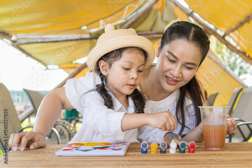 The Asian mother and daughter do a happy painting activity together.