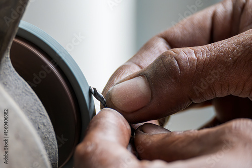 The small drill tool regrind process by manual operation with abrasive wheel.