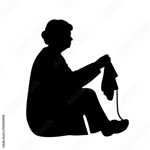 Elderly woman knitting while sitting on the floor in silhouette  