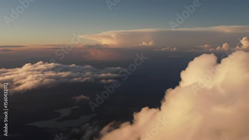 Aerial sunset view showcasing a breathtaking expanse of fluffy clouds illuminated by warm, golden light.