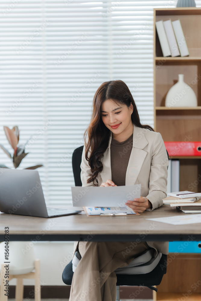 Confident Professional: An attractive and focused professional woman sits at her desk, reviewing financial documents in a modern office setting. She exemplifies dedication and success. Confident Professional: An attractive and focused professional woman sits at her desk, reviewing financial documents in a modern office setting. She exemplifies dedication and success.