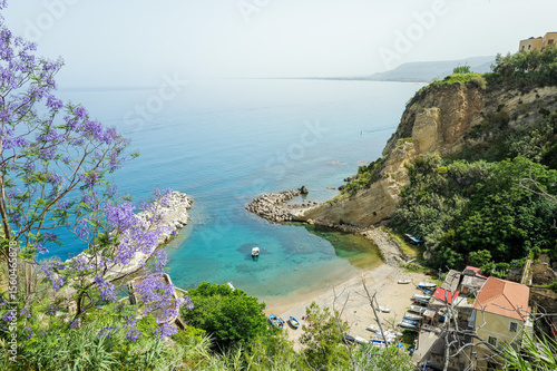 Bild auf Leinwand Italian Coastal Serenity — Aerial View of Sea with Boat and Purple Flowers