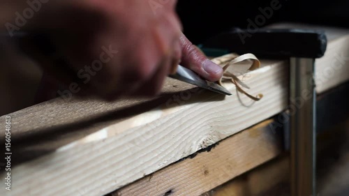 Carpenter working with a sharp chisel in a small woodworking shop.