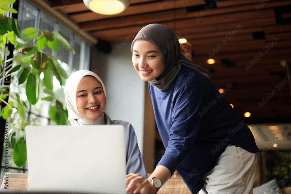 Two Muslim Friends Wearing Hijab Working on Laptop at Coffee Shop Two Muslim Friends Wearing Hijab Working on Laptop at Coffee Shop