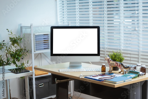 Wallpaper Mural A clean, organized veterinary clinic workspace featuring a desktop computer with a blank screen, anatomical dog model, stethoscope, medicine bottles, calculator, and document shelves Torontodigital.ca