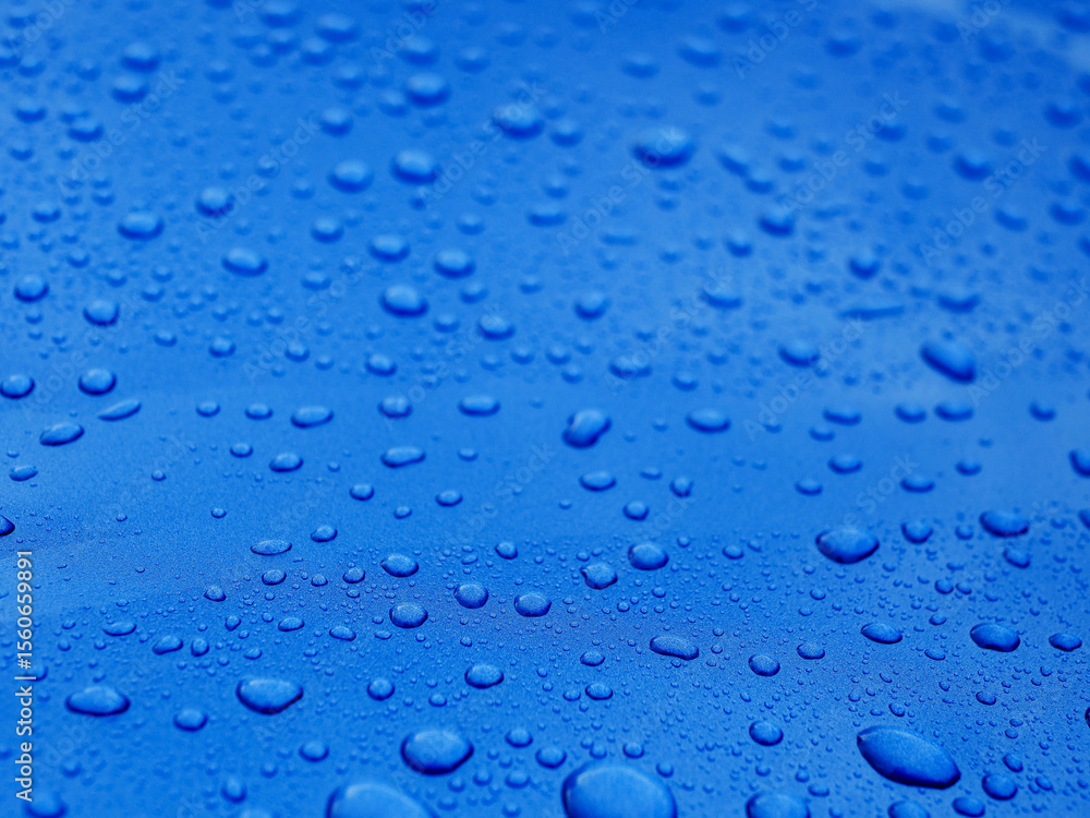 The image is of a blue surface with many small drops of water on it. The drops are scattered all over the surface, creating a sense of movement and energy. Background for design with rich color The image is of a blue surface with many small drops of water on it. The drops are scattered all over the surface, creating a sense of movement and energy. Background for design with rich color
