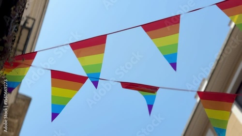 Street decorated with rainbow flags for Pride. Urban architecture, balconies, LGBT celebration, equality symbol, love, inclusion, and support for the LGBTQ+ community